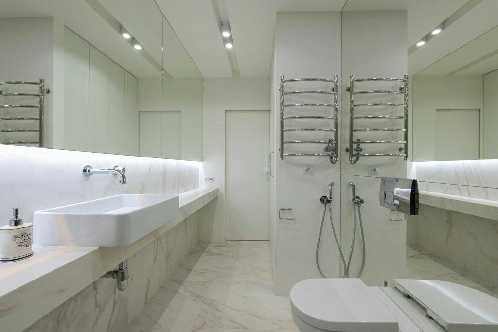 Interior design of modern restroom with toilet under mirror with sink and faucet on opposite wall